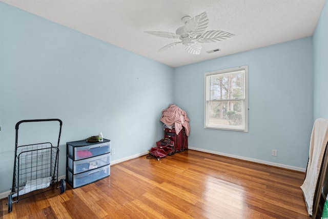 miscellaneous room featuring ceiling fan, hardwood / wood-style floors, and a textured ceiling