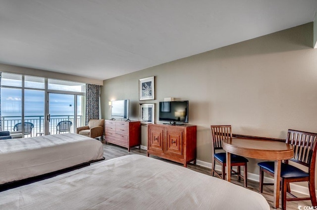 bedroom featuring access to exterior, baseboards, and wood finished floors