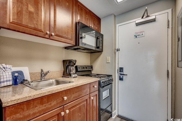 kitchen with brown cabinets, light countertops, a sink, and black appliances