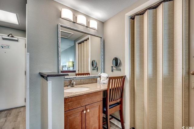 bathroom featuring a textured wall, wood finished floors, and vanity