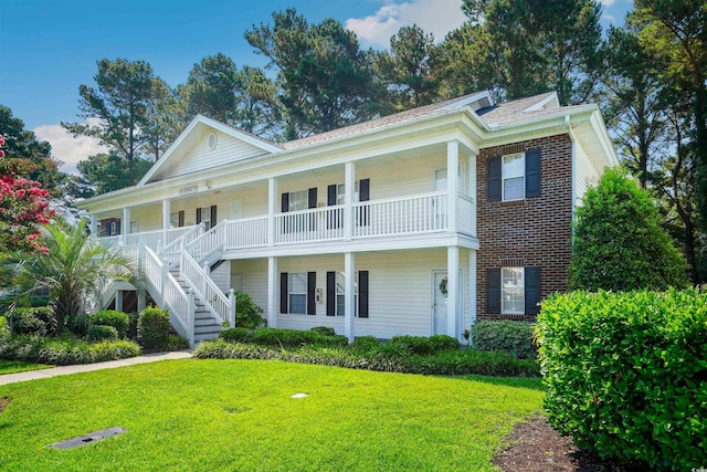 view of front of home with a front yard, a porch, and a balcony