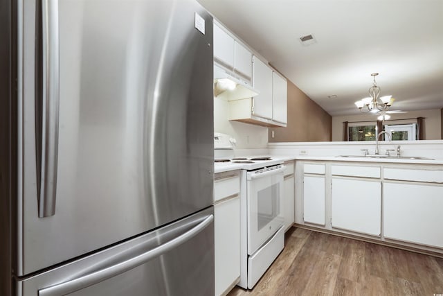 kitchen featuring an inviting chandelier, white electric range, stainless steel refrigerator, white cabinets, and sink