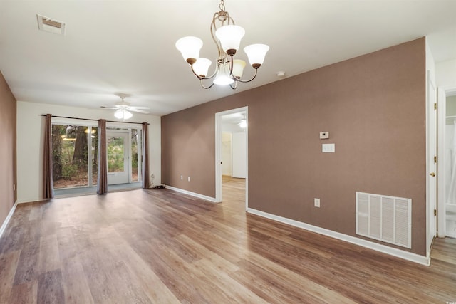 empty room with ceiling fan with notable chandelier and light hardwood / wood-style floors