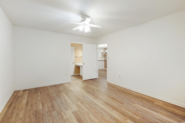 empty room featuring ceiling fan with notable chandelier and light hardwood / wood-style flooring