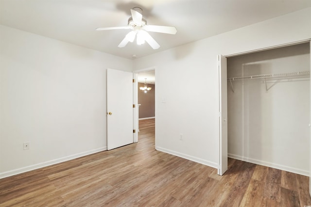 unfurnished bedroom with a closet, ceiling fan with notable chandelier, and wood-type flooring