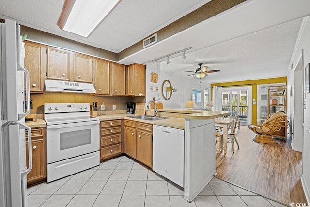 kitchen with white appliances, kitchen peninsula, ceiling fan, sink, and light tile patterned flooring