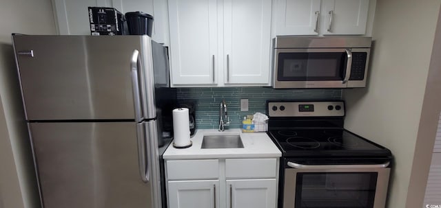 kitchen featuring stainless steel appliances, white cabinets, sink, and backsplash