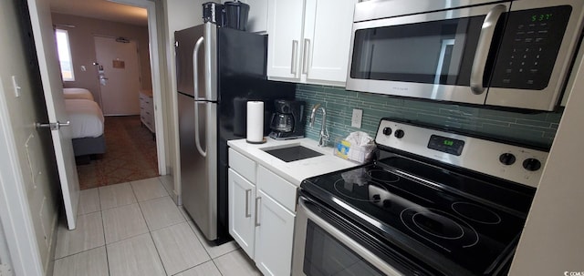 kitchen featuring sink, stainless steel appliances, light tile patterned floors, and white cabinets