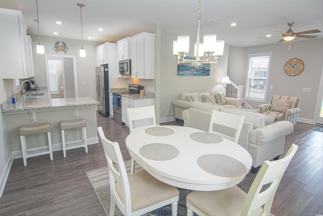 dining area with sink, dark hardwood / wood-style flooring, and ceiling fan with notable chandelier