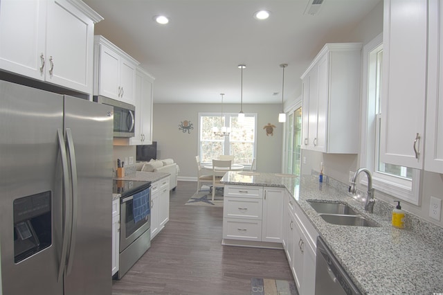 kitchen with stainless steel appliances, white cabinetry, sink, and kitchen peninsula