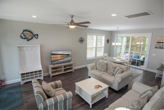 living room featuring ceiling fan with notable chandelier and dark wood-type flooring