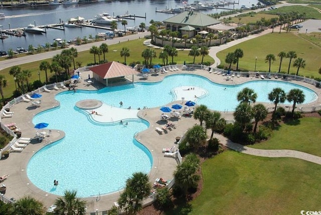 view of swimming pool with a patio area, a yard, and a water view