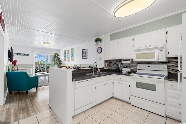 kitchen with white appliances, kitchen peninsula, sink, white cabinetry, and backsplash