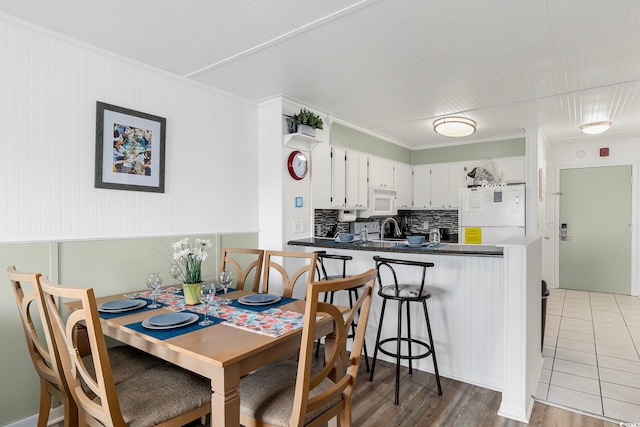 dining room with sink, crown molding, and hardwood / wood-style flooring