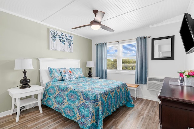 bedroom with a wall mounted AC, ceiling fan, crown molding, and wood-type flooring