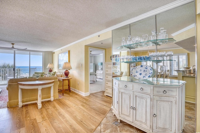 kitchen with ceiling fan, light hardwood / wood-style floors, crown molding, and a textured ceiling