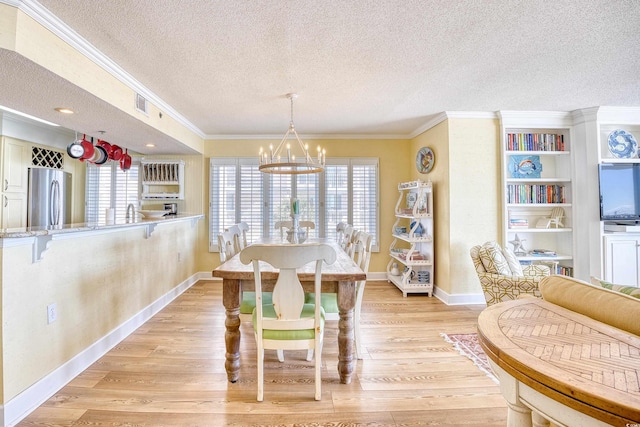 dining area with light wood-type flooring, a notable chandelier, crown molding, and a textured ceiling