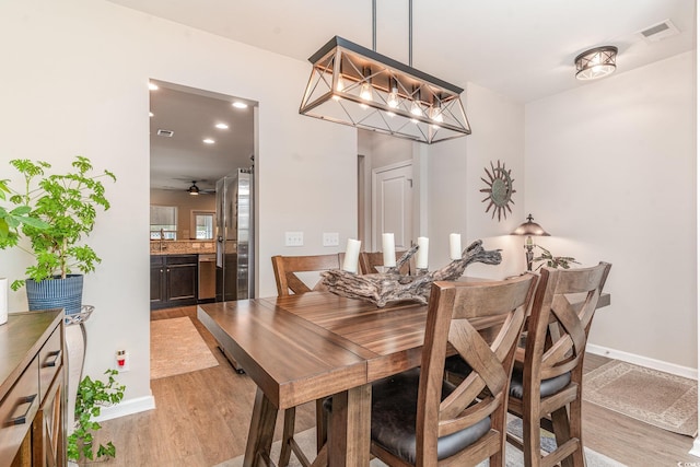 dining area with an inviting chandelier and light hardwood / wood-style flooring