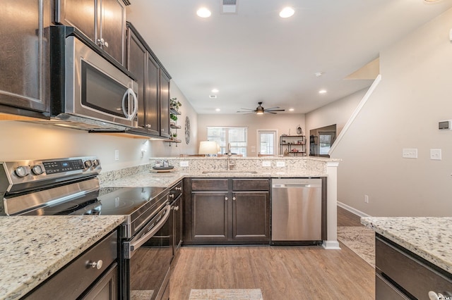 kitchen featuring dark brown cabinetry, sink, light hardwood / wood-style flooring, kitchen peninsula, and stainless steel appliances