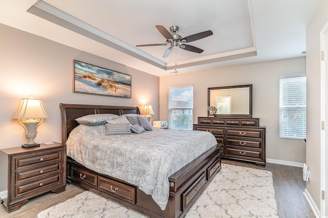 bedroom with a raised ceiling, crown molding, ceiling fan, and light hardwood / wood-style floors