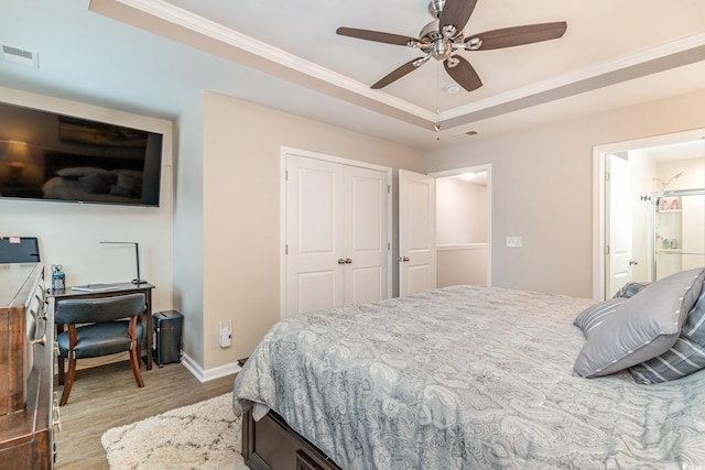 bedroom featuring a tray ceiling, ornamental molding, ceiling fan, light hardwood / wood-style floors, and a closet