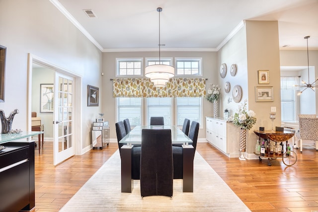 dining room with crown molding, a notable chandelier, and light hardwood / wood-style flooring