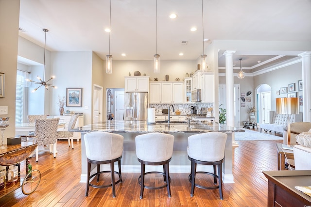 kitchen with a chandelier, pendant lighting, white cabinetry, dark stone counters, and appliances with stainless steel finishes