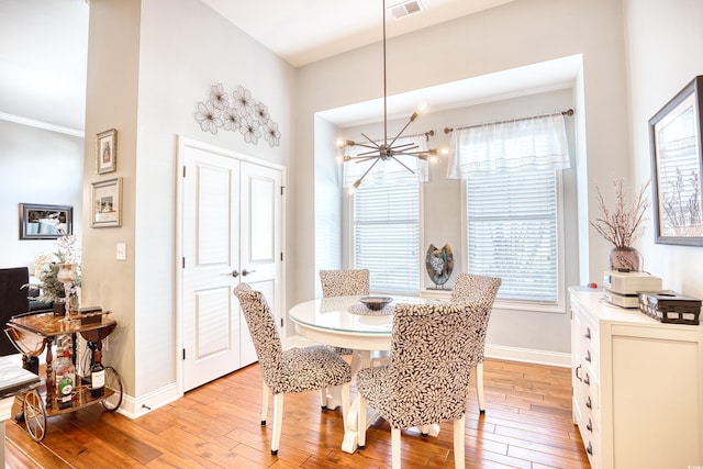 dining area featuring a chandelier, light wood-type flooring, and crown molding