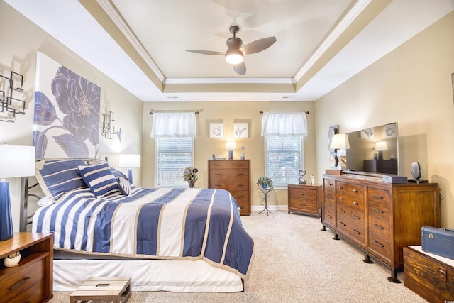 bedroom with ceiling fan, a tray ceiling, crown molding, and light colored carpet