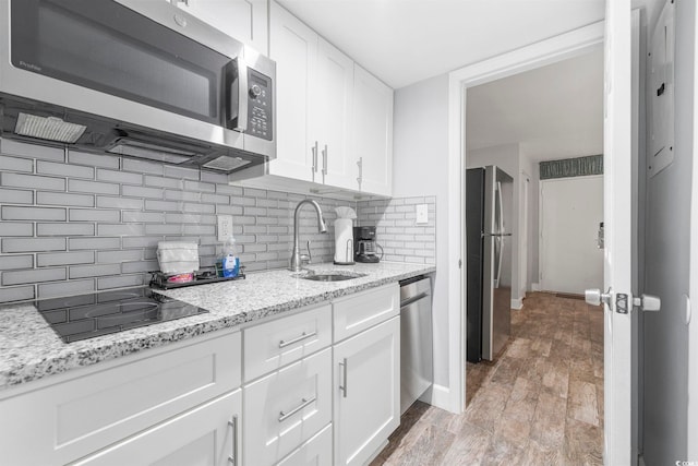 kitchen featuring sink, light stone countertops, white cabinets, and appliances with stainless steel finishes