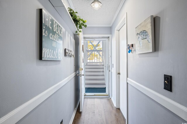 doorway featuring a textured ceiling, hardwood / wood-style floors, and ornamental molding