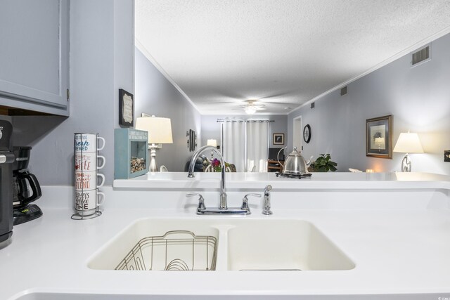 kitchen featuring sink, a textured ceiling, ceiling fan, and ornamental molding