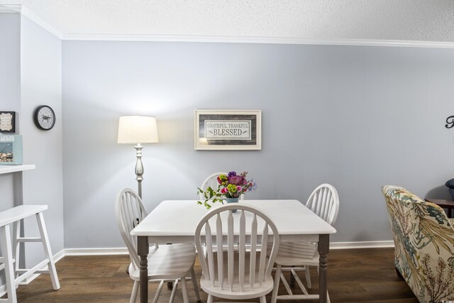 dining room with dark hardwood / wood-style flooring, a textured ceiling, and ornamental molding