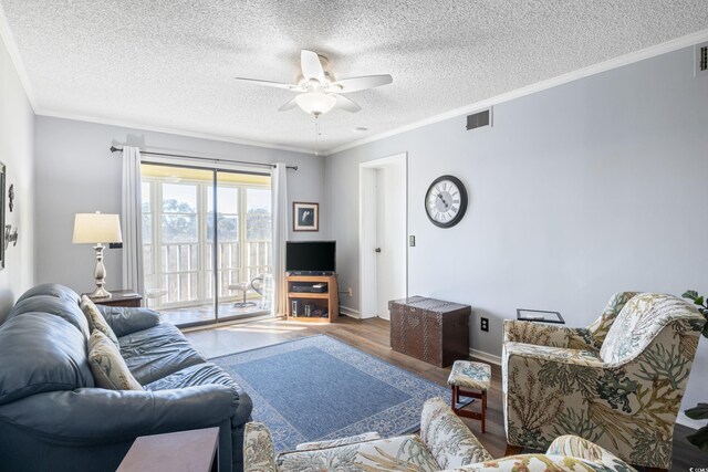 living room with ceiling fan, ornamental molding, a textured ceiling, and wood-type flooring