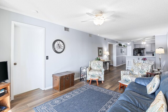 living room with dark wood-type flooring, a textured ceiling, and ceiling fan