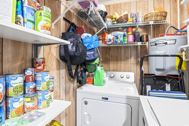 clothes washing area featuring wooden walls, water heater, and washing machine and clothes dryer