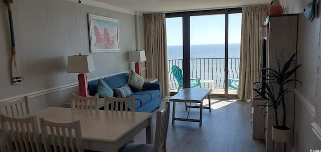 living room featuring hardwood / wood-style flooring, a wall of windows, crown molding, and a water view