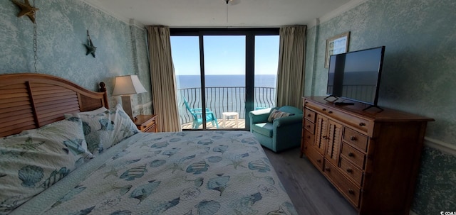 bedroom with a wall of windows, access to exterior, and hardwood / wood-style floors