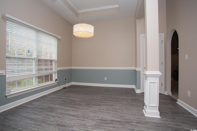 empty room featuring baseboards, a tray ceiling, decorative columns, arched walkways, and dark wood-style floors