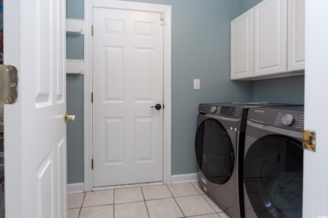 laundry area featuring light tile patterned floors, cabinet space, baseboards, and separate washer and dryer