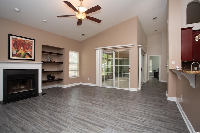 unfurnished living room with dark wood finished floors, a fireplace with flush hearth, baseboards, and ceiling fan