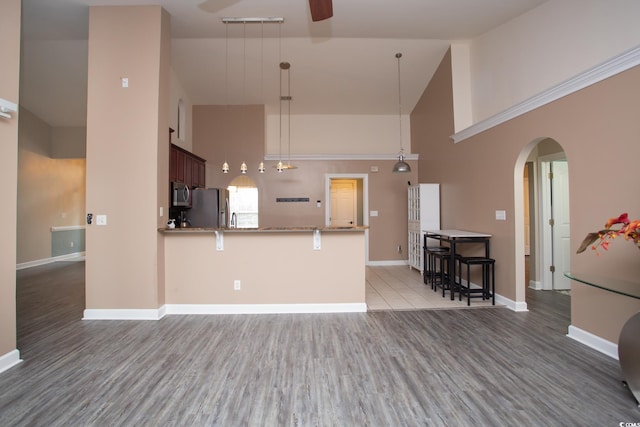 kitchen with ceiling fan, high vaulted ceiling, arched walkways, and stainless steel appliances