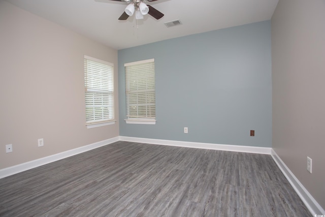 unfurnished room with dark wood-type flooring, baseboards, visible vents, and ceiling fan