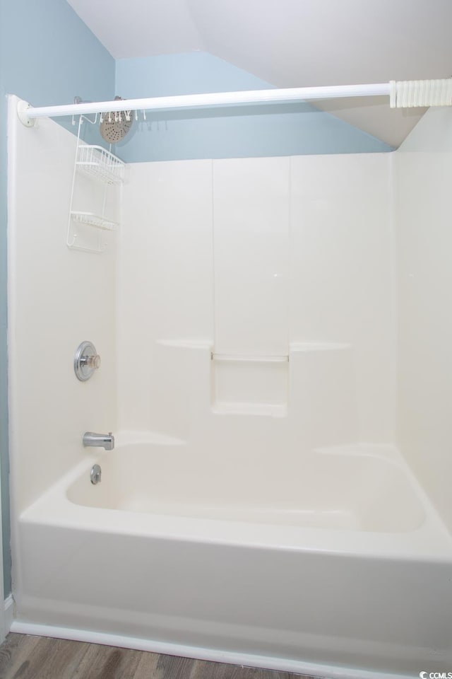 bathroom with tub / shower combination, lofted ceiling, and wood finished floors