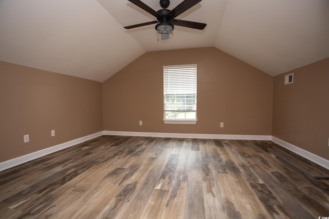 additional living space featuring dark wood finished floors, visible vents, baseboards, and vaulted ceiling