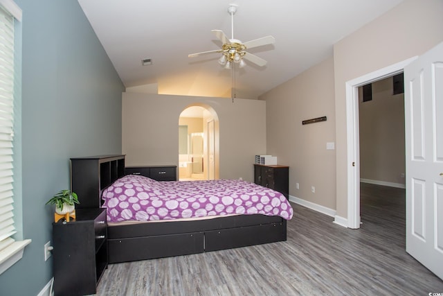 bedroom with visible vents, lofted ceiling, wood finished floors, arched walkways, and baseboards