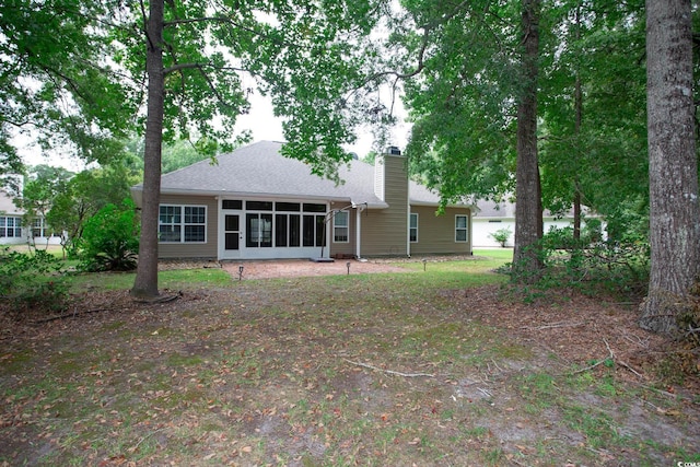 rear view of property with roof with shingles, a sunroom, and a chimney