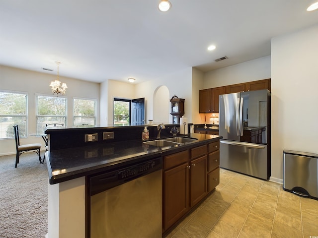 kitchen featuring decorative light fixtures, stainless steel appliances, an inviting chandelier, sink, and a kitchen island with sink