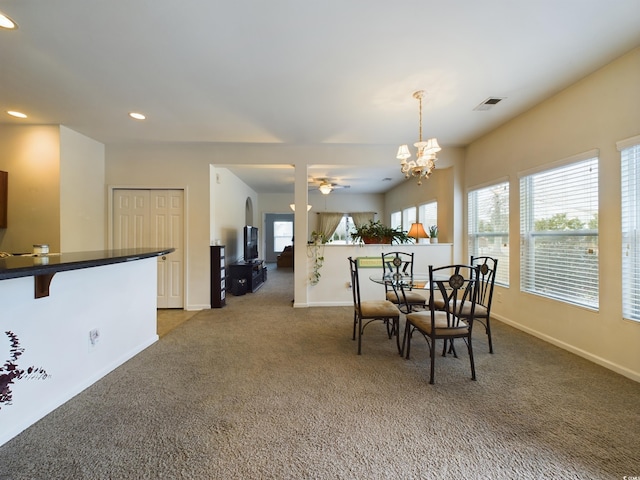 carpeted dining area with ceiling fan with notable chandelier