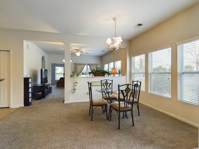 carpeted dining room with baseboards, visible vents, and ceiling fan with notable chandelier